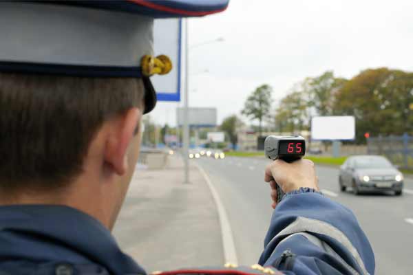 A police office checking car speeds with a radar.