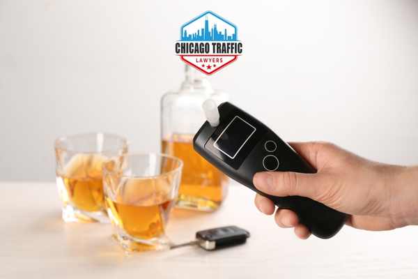 a person holding a breathalyzer test in front of car keys and alcohol glasses on a table