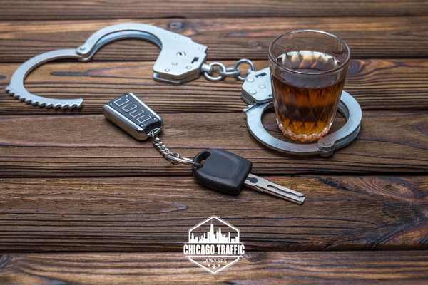 car keys, handcuffs, and a glass of whiskey on a table